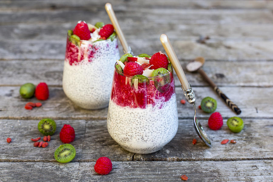 Two glasses of chia pudding with cocos, raspberry sauce and several fruits Photograph by Westend61