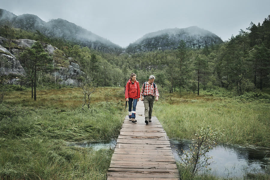 Two hikers passing through a brook on wooden bridge Photograph by Stanislaw Pytel