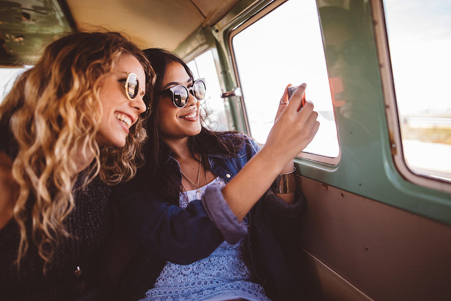 Two Hipster Girls Sitting Together taking a road trip photo Photograph by Wundervisuals