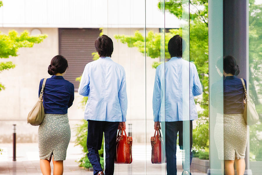 Two Japanese business people walking side by side rear view Photograph by NicolasMcComber