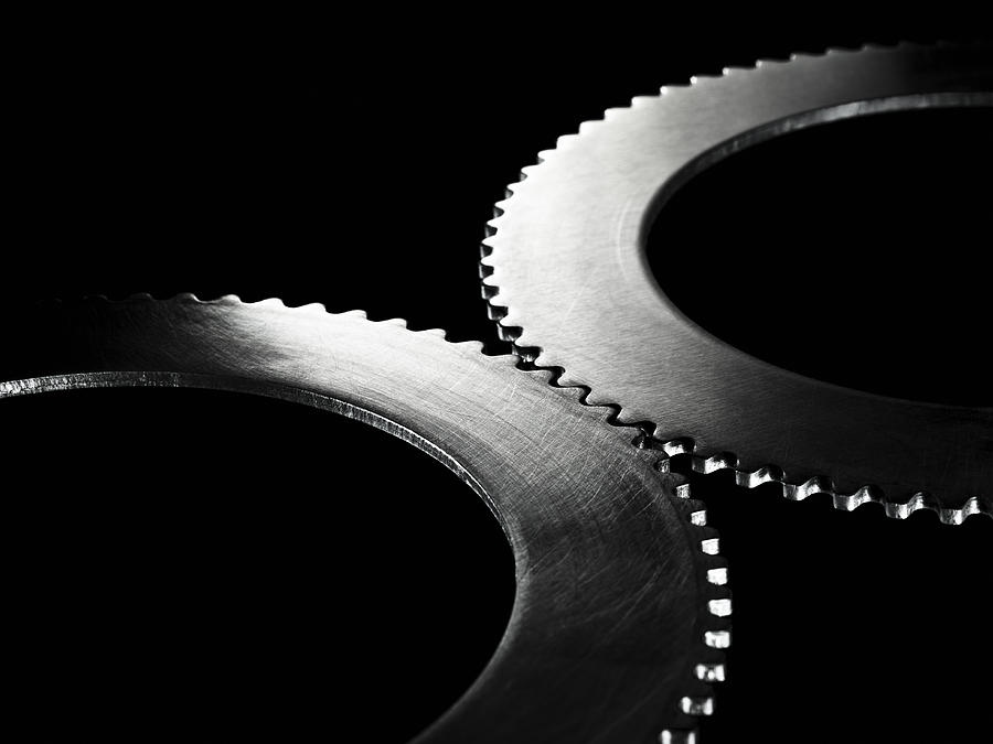 Two linked steel gear / cogs on black background Photograph by Pier