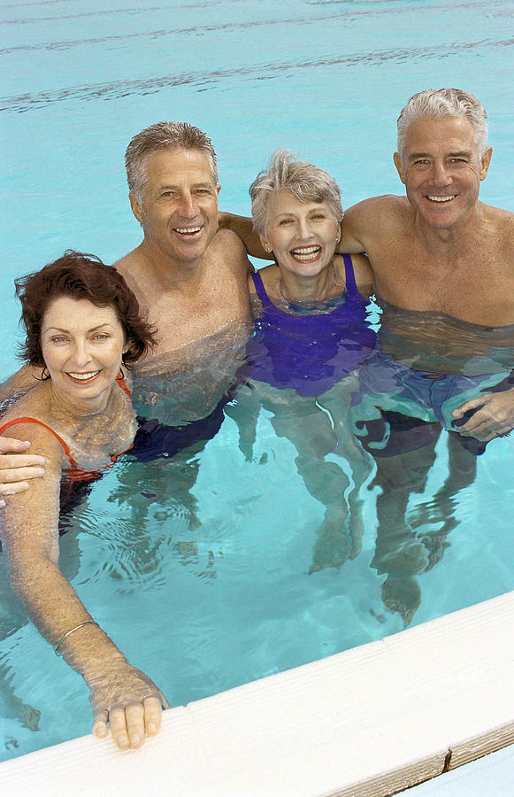 Two mature couples standing in swimming pool Photograph by Vincent Hazat