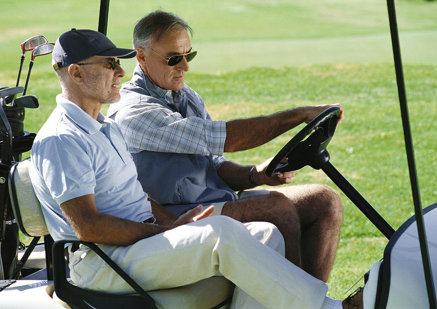 Two mature golfers in golf cart, close-up, side view Photograph by Vincent Hazat