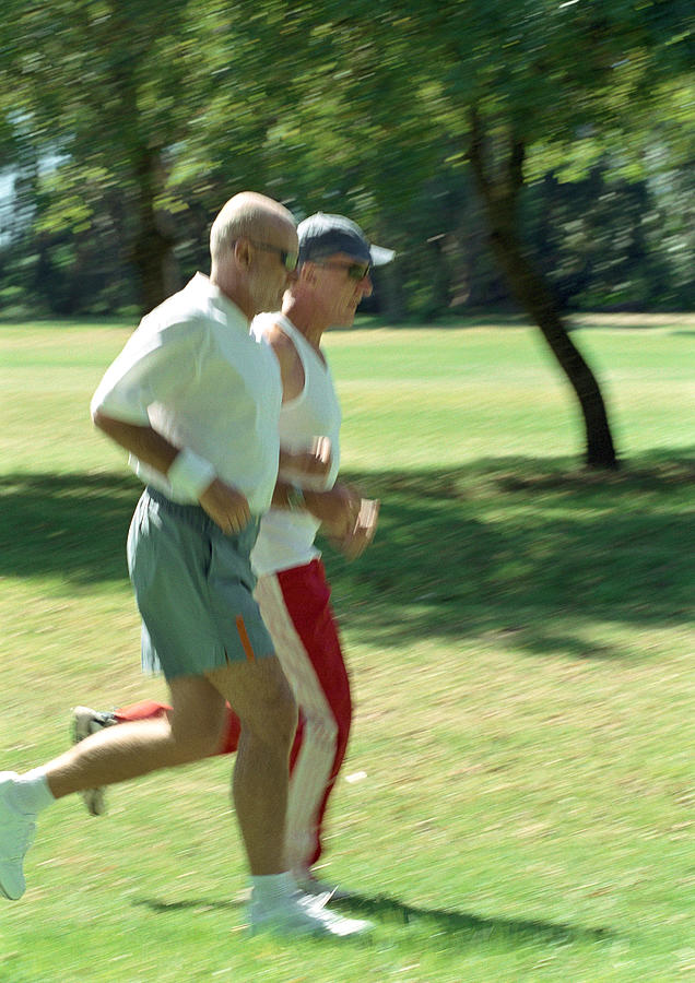 Two mature joggers in park, side view Photograph by Vincent Hazat