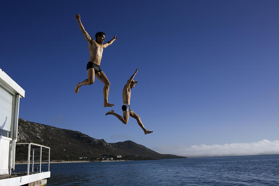 Two men jumping off of houseboat Photograph by Smile
