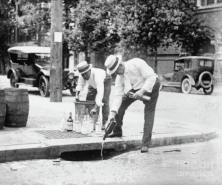 Two men pouring liquor into storm drain, 8 July 1921 Photograph by American School
