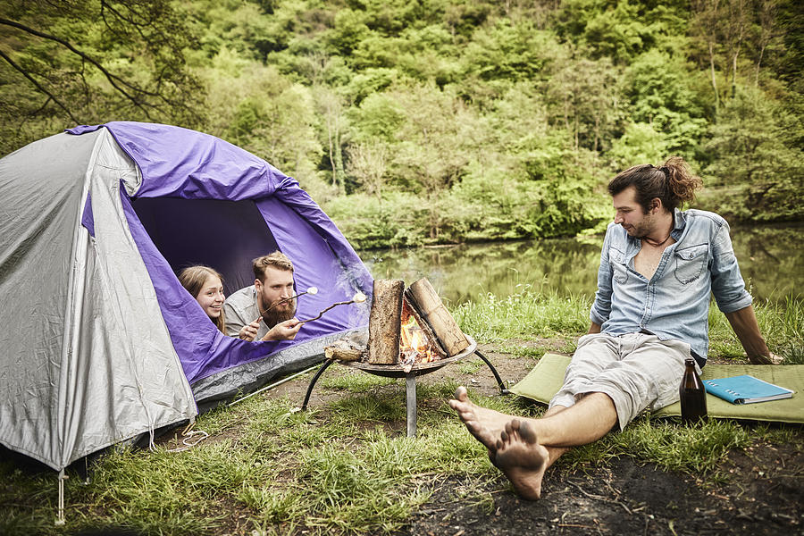Two men with girl and tent at camp fire Photograph by Oliver Rossi
