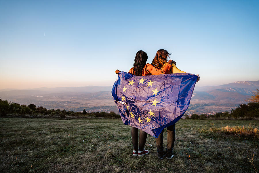 Two multi-ethnic women holding European Union flag Photograph by Urbazon