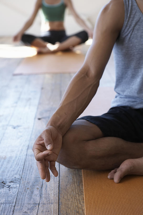 Two people in yoga class, low section (focus on man meditating) Photograph by Thomas Northcut