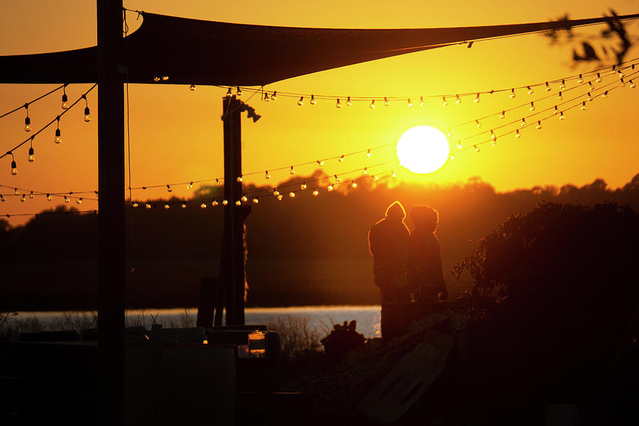Two people standing by the water at sunset Bowen's Island South