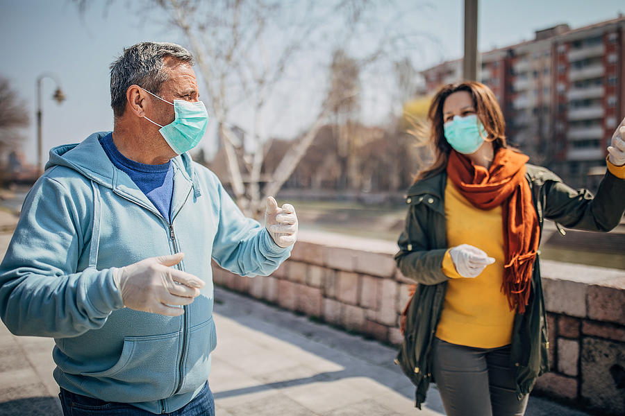 Two people with protective mask walking on the street in safe distance Photograph by South_agency
