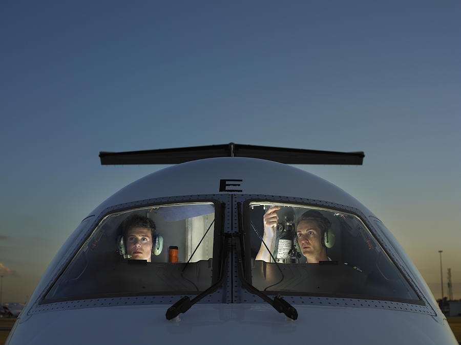 Two pilots in cockpit of plane, view through glass Photograph by Adrian Weinbrecht