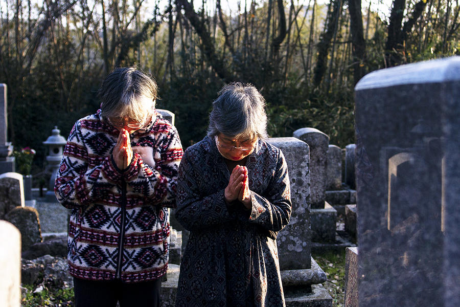 Two senior Japanese women put their hands together in graveyard Photograph by Masaru123
