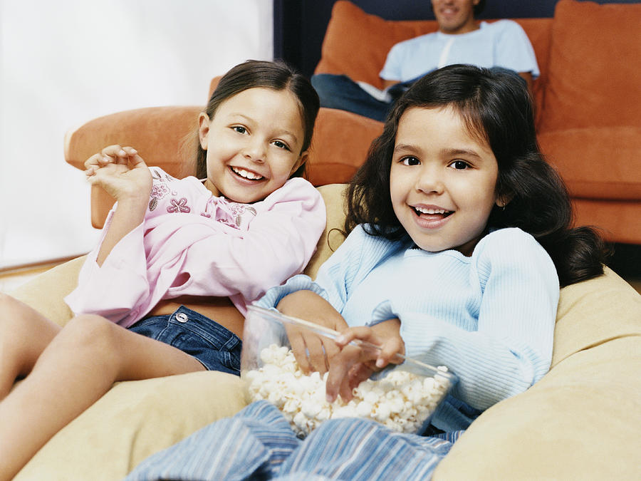 Two Sisters Sitting on a Beanbag With a Bowl of Popcorn Photograph by Digital Vision.
