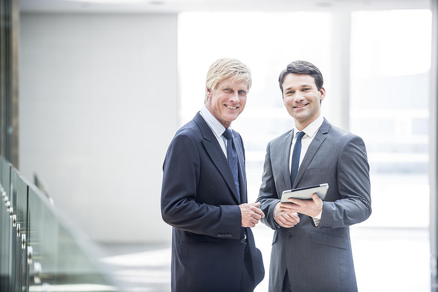 Two smiling businessman with digital tablet Photograph by JohnnyGreig