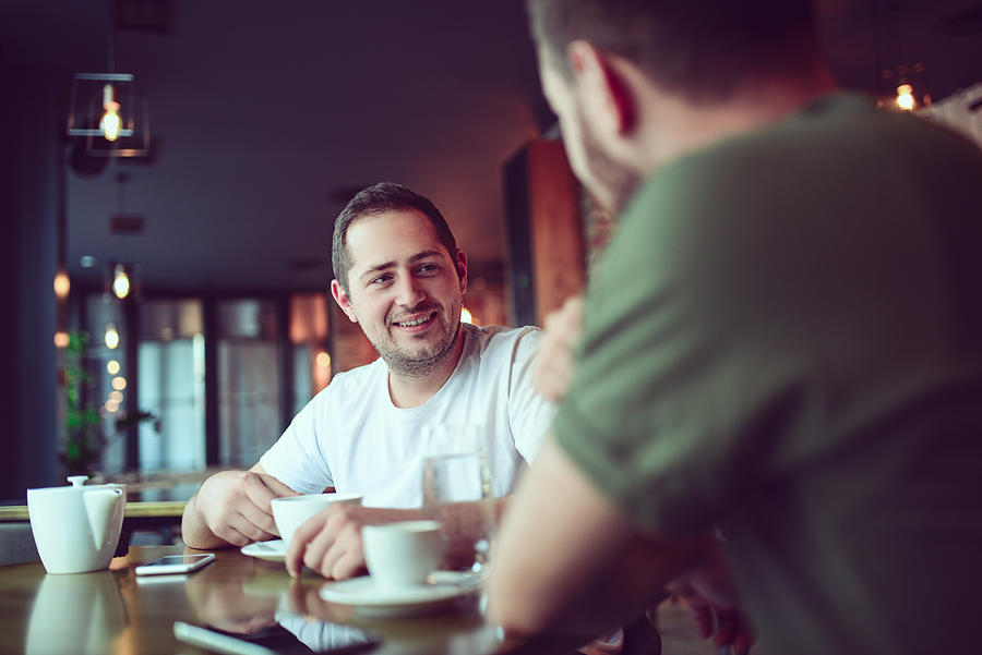 Two Smiling Friends Drinking Coffee and Socialising in a Cafe Photograph by AleksandarGeorgiev