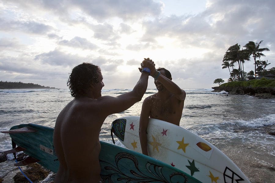 Two surfers high five on the beach Photograph by Noel Hendrickson