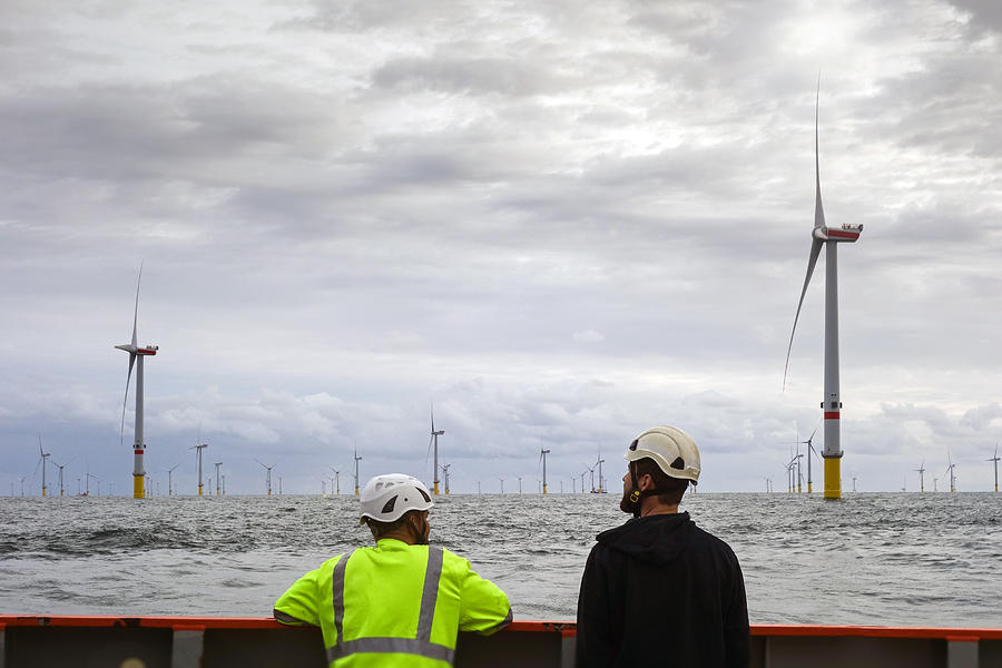 Two Technician standing on transfer vessel deck and in the morning and looking on offshore wind farm and offshore platform around Photograph by CharlieChesvick