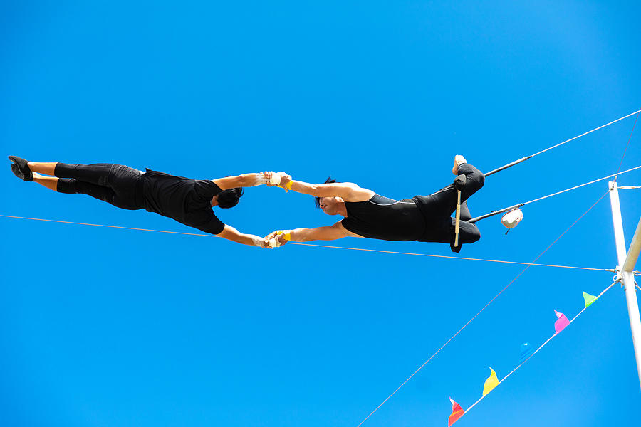 Two trapeze artists flying together in the sky Photograph by Satoshi-K