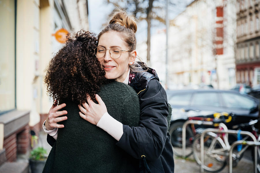 Two Women Greeting One Another In The Street Photograph by Tom Werner