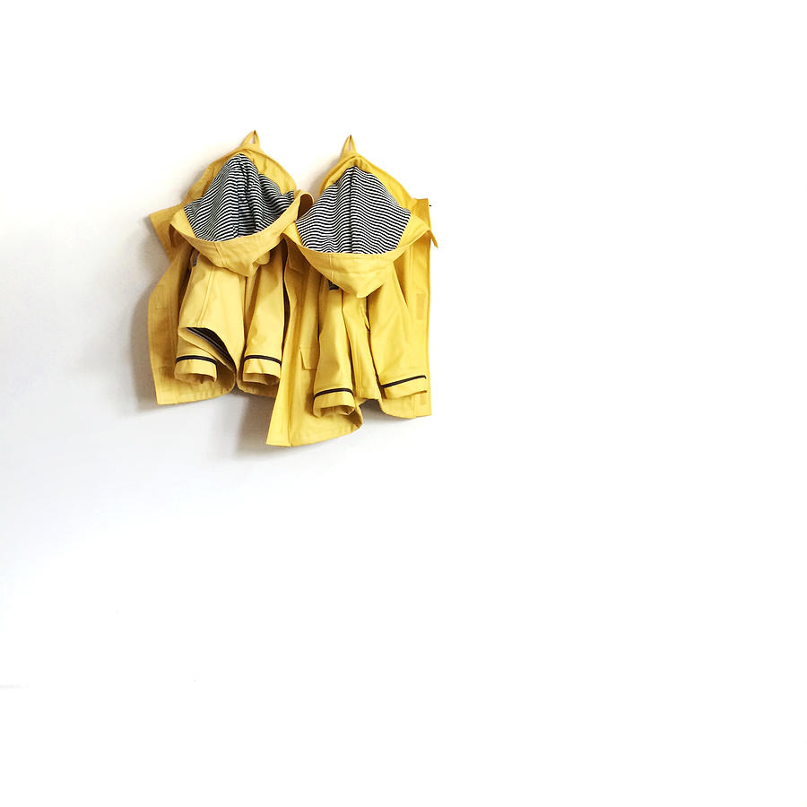 Two yellow raincoats hanging on wall Photograph by Hannahargyle