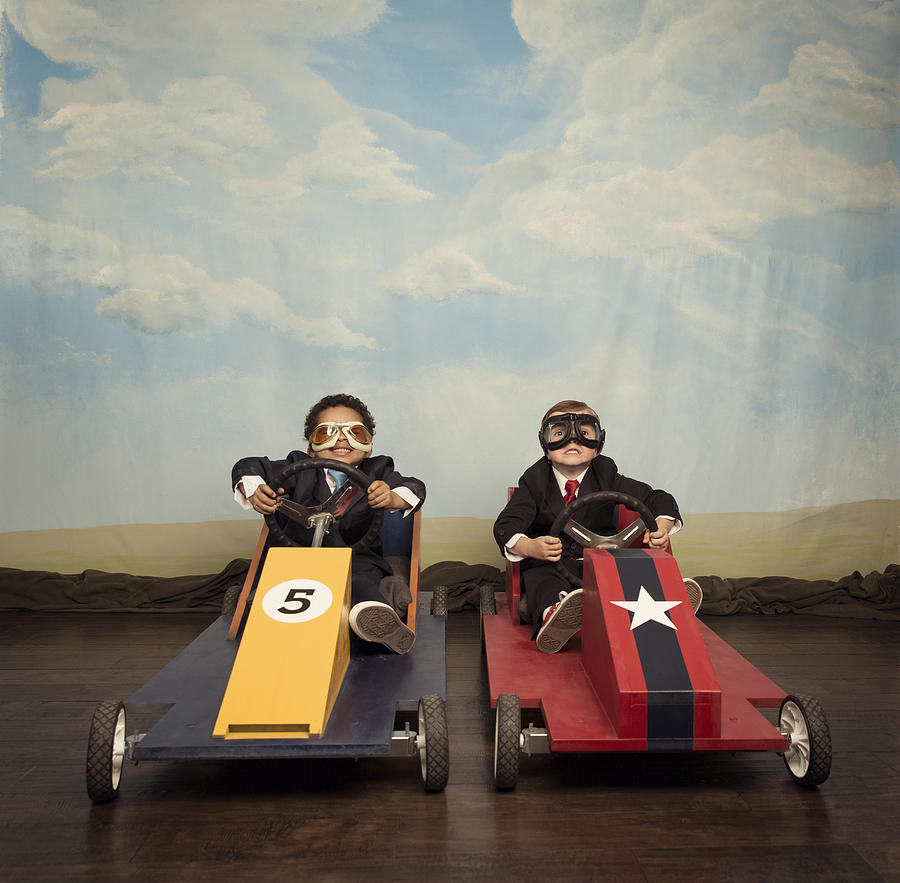 Two young businessmen race each other in toy cars Photograph by RichVintage