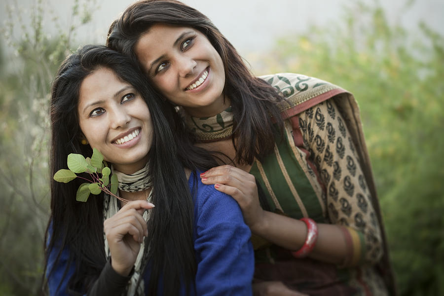 Two young Indian women sitting outdoor in natural area. Photograph by Gawrav