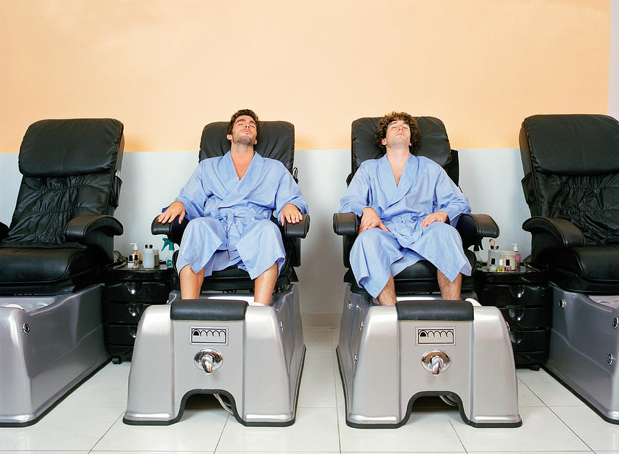 Two young men at spa soaking feet before pedicure Photograph by Leland Bobbe