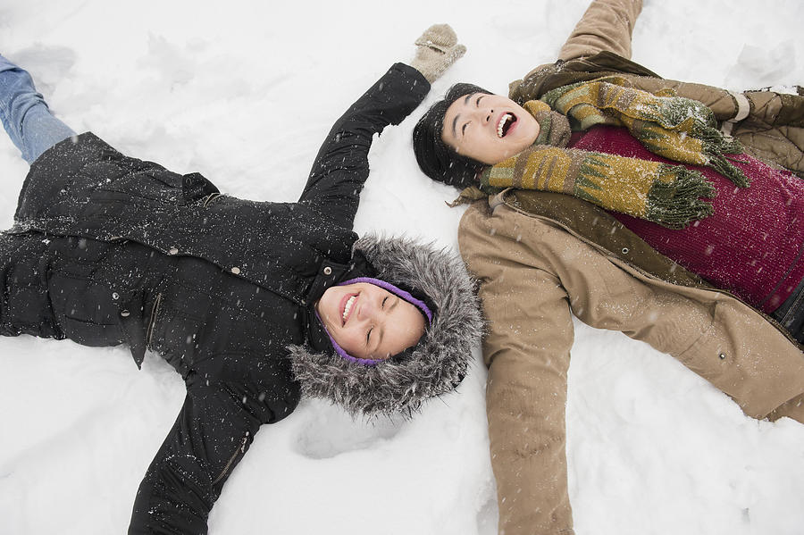 Two young people making snow angels Photograph by Jamie Grill