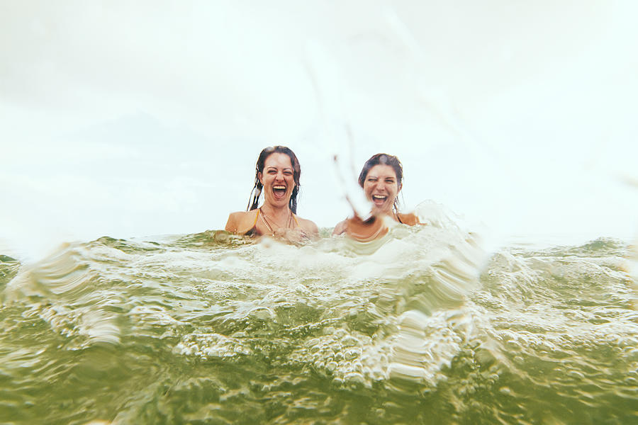 Two young woman splashing ocean water Photograph by Brook Pifer