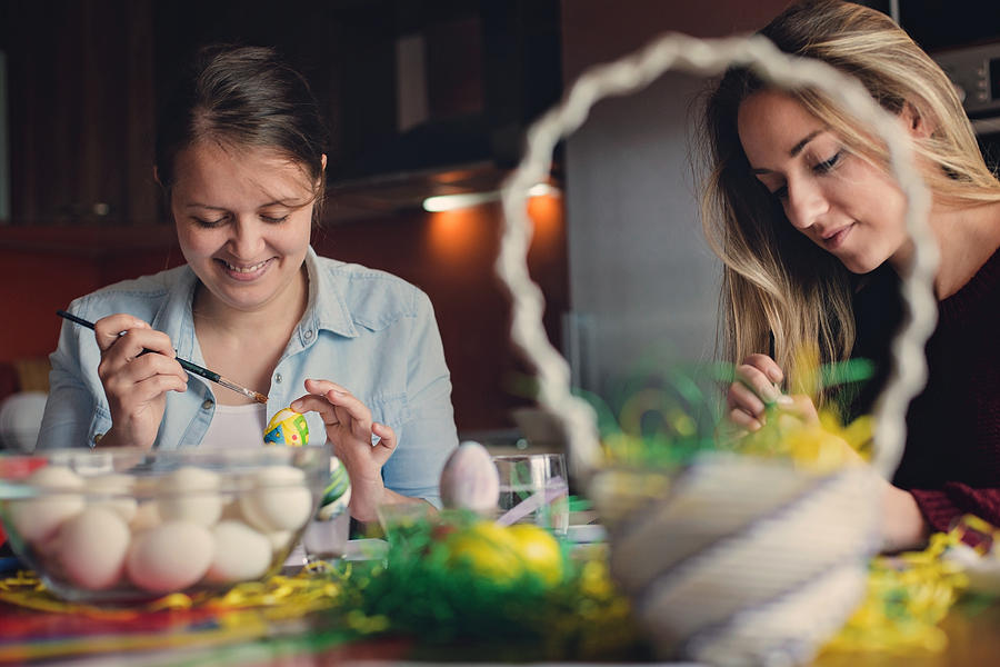 Two young women coloring eggs for Easter Photograph by Aywan88