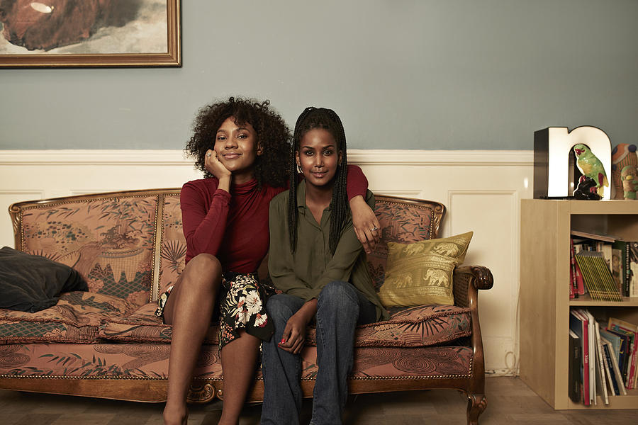 Two young women in sofa at home Photograph by Klaus Vedfelt