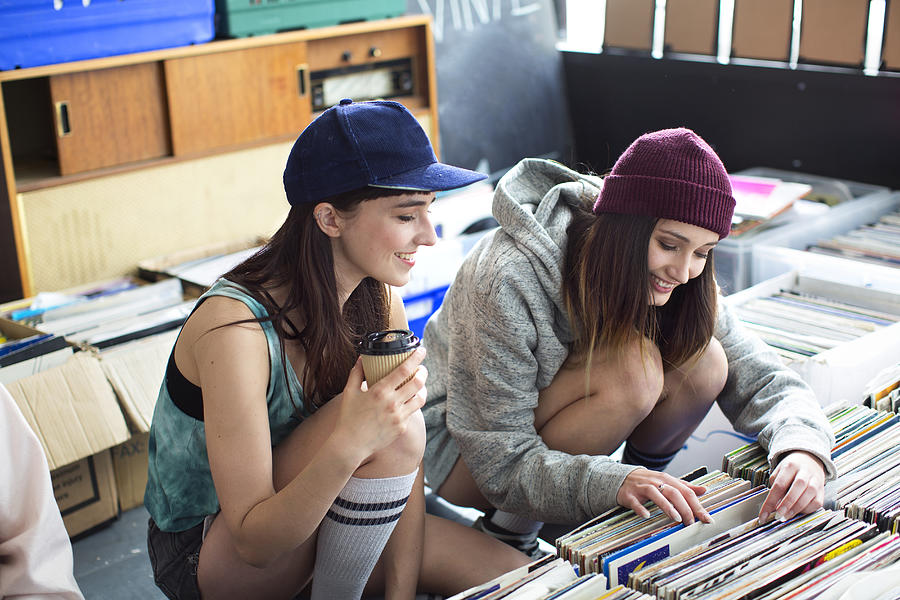Two young women looking at records in store Photograph by Michael Heffernan