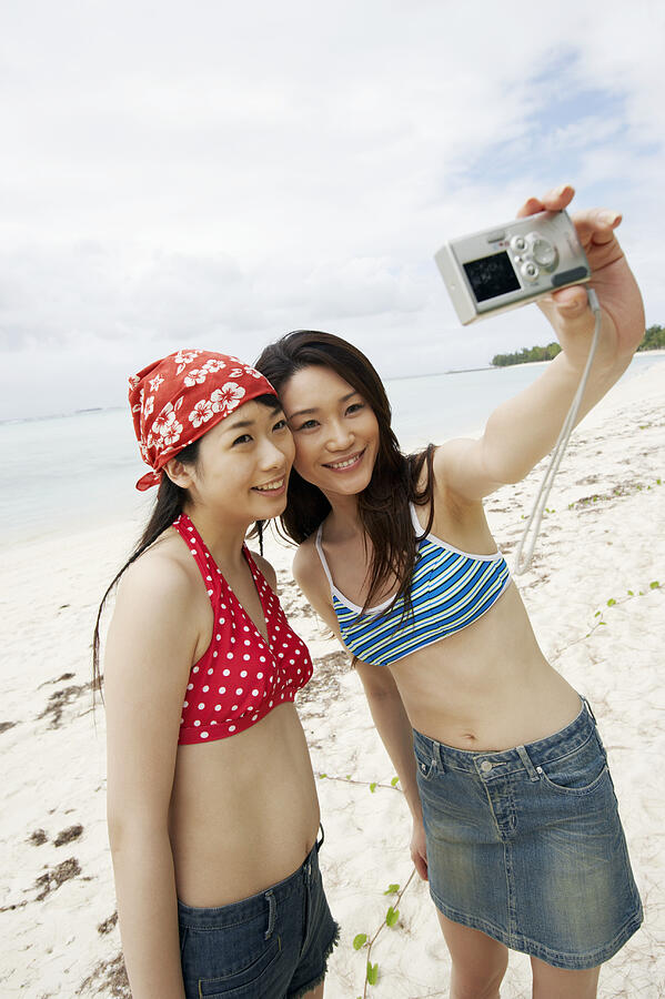 Two Young Women Taking a Self Portrait on the Beach With a Digital Camera Photograph by Dex
