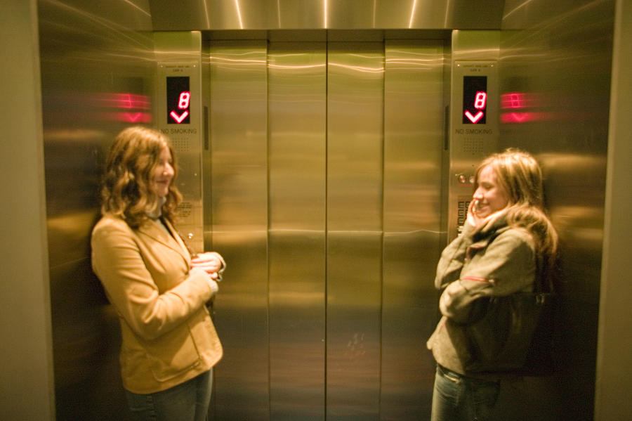 Two young women waiting in elevator Photograph by Photodisc