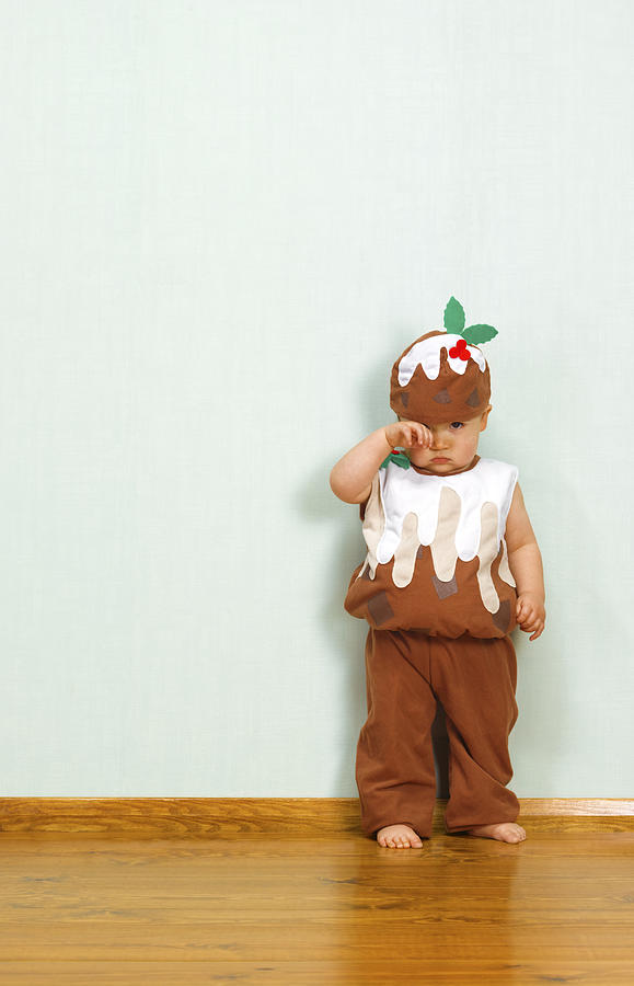 Unhappy baby boy in christmas pudding outfit Photograph by Peter Dazeley