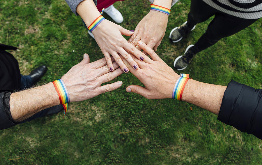 Unity hands of diverse people with multicolored bracelet Photograph by Karrastock