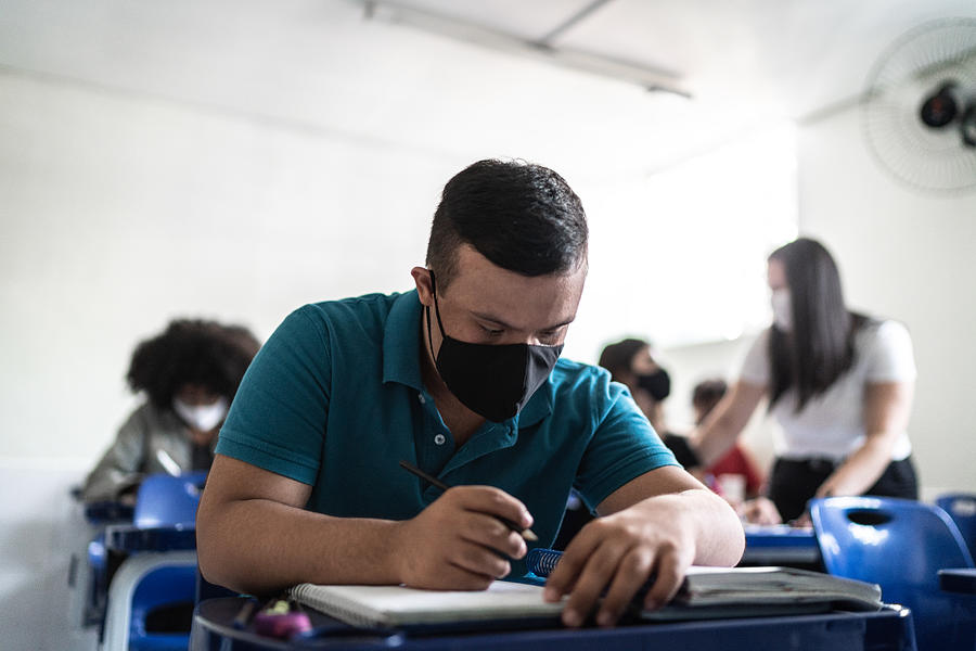 University / high school student with down syndrome wearing face mask while studying in the classroom Photograph by FG Trade