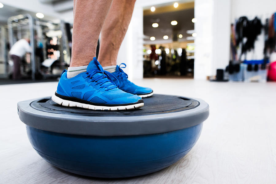 Unrecognizable senior man in gym standing on bosu balance ball Photograph by Halfpoint