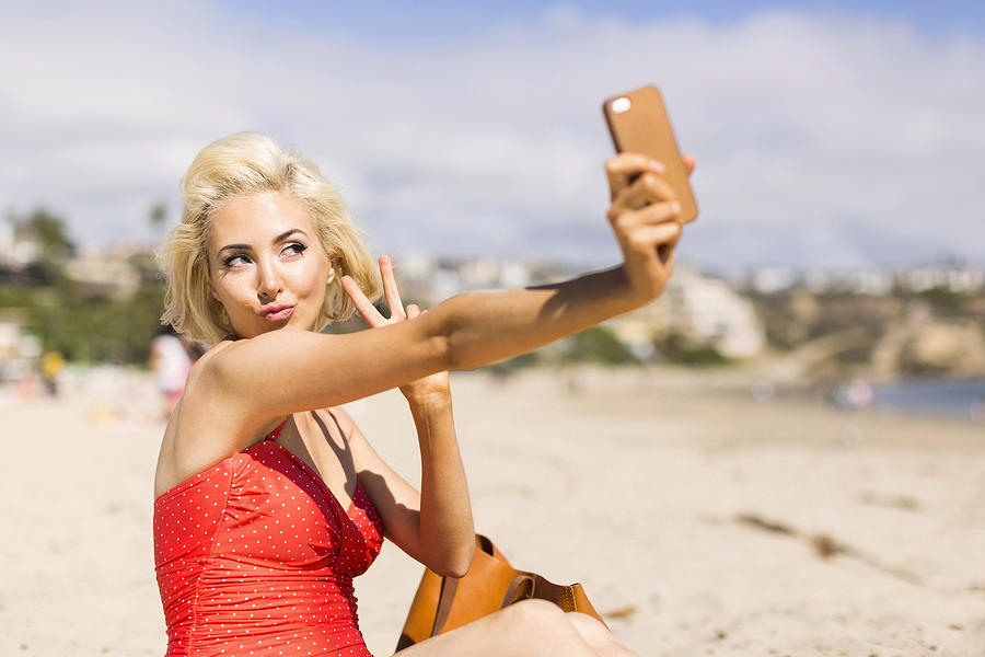 USA, California, Costa Mesa, Blond woman taking selfie on beach Photograph by Jessica Peterson