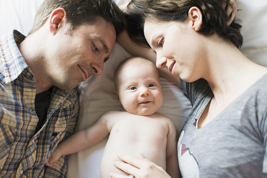 USA, California, Orange County, Parents and baby son (2-5 months) lying on bed Photograph by Jessica Peterson