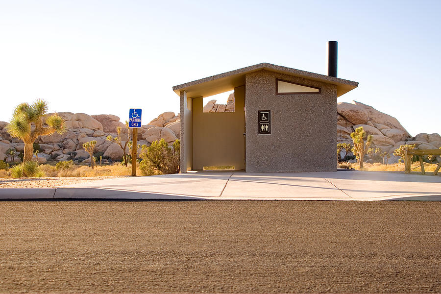 USA, California, Palm Springs, roadside public toilet building, Joshua trees and rock formation in background Photograph by George Diebold