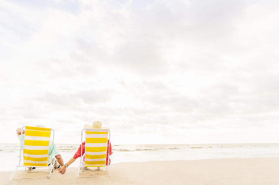 USA, Florida, Jupiter, Rear view of couple sitting in lounge chairs on beach  Photograph by Daniel Grilll