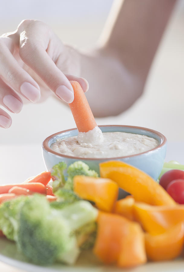 USA, New Jersey, Jersey City, Close-up view of woman hand putting baby carrot into dip Photograph by Jamie Grill Photography