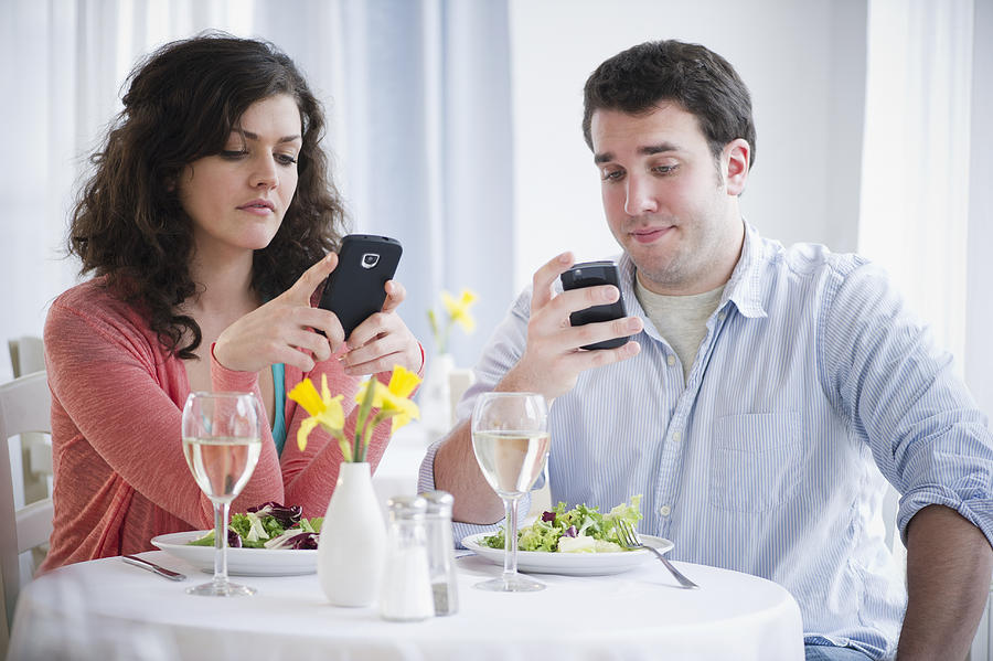 USA, New Jersey, Jersey City, Couple having dinner and text messaging Photograph by Jamie Grill