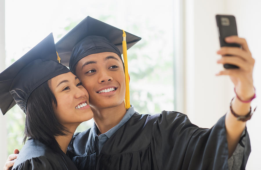 USA, New Jersey, Jersey City, Portrait of young woman and young man wearing graduation gown Photograph by Daniel Grill