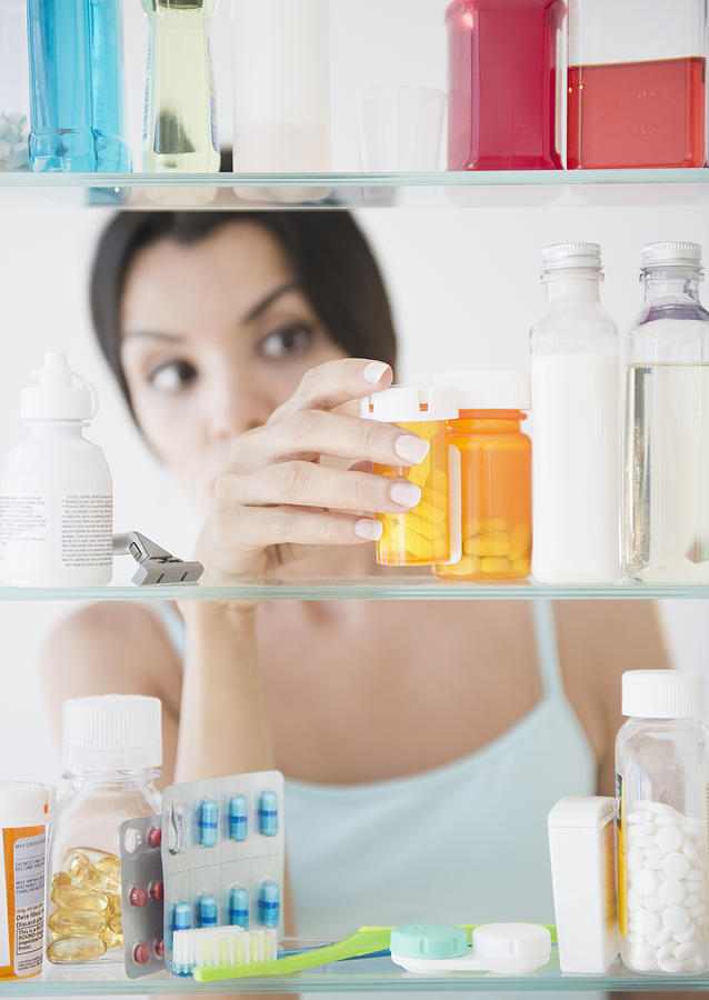 USA, New Jersey, Jersey City, Woman taking medicine from cabinet Photograph by Jamie Grill