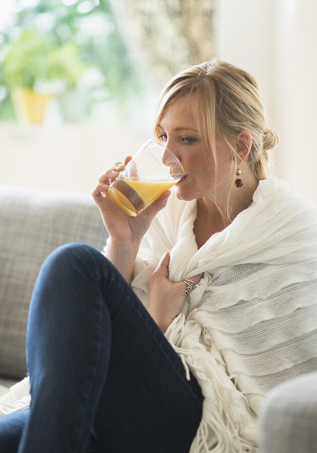 USA, New Jersey, Woman sitting on sofa and drinking orange juice Photograph by Tetra Images