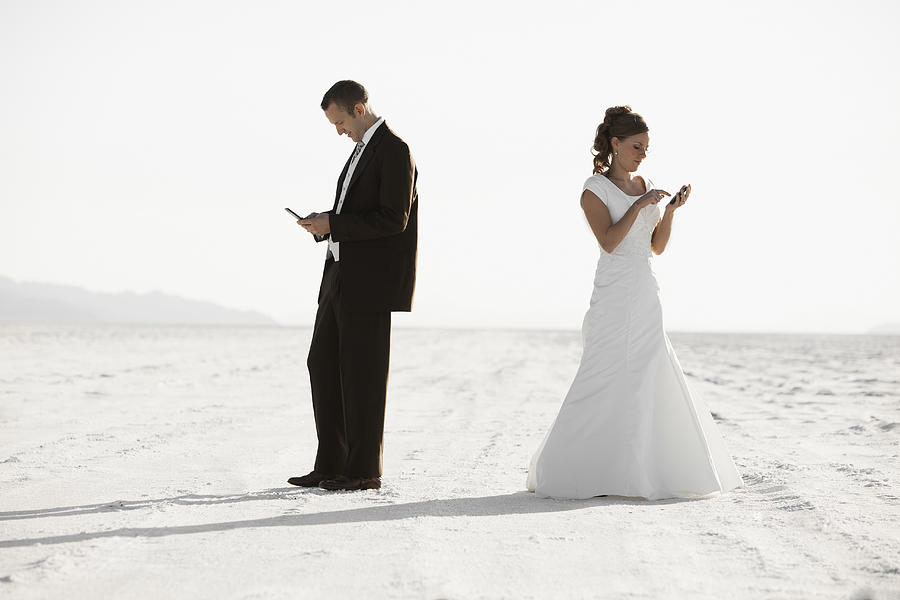 USA, Utah, Boneville Salt Flats, Bride and groom texting in desert Photograph by Fbp USA, Utah, Boneville Salt Flats, Bride and groom texting in desert Photograph by Fbp