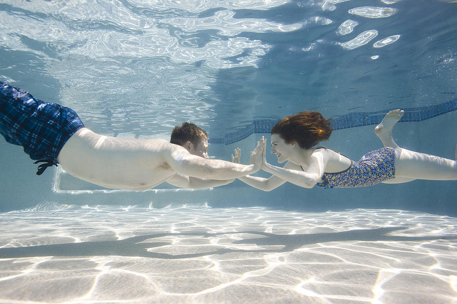 USA, Utah, Orem, Happy young couple holding hands in swimming pool Photograph by Nicole Hill Gerulat